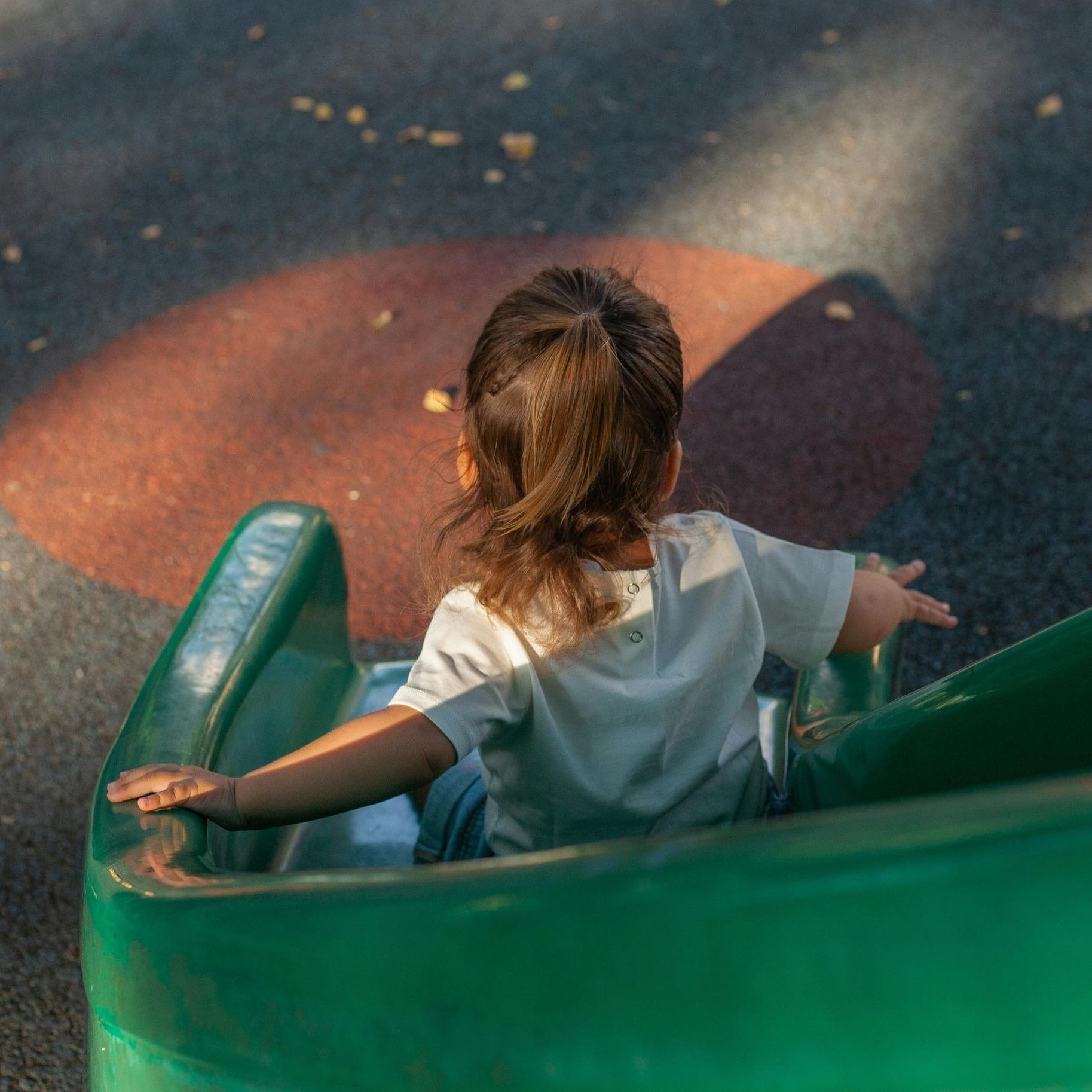 Child sliding down a green playground slide on a sunny day near Northside Vistas apartments.