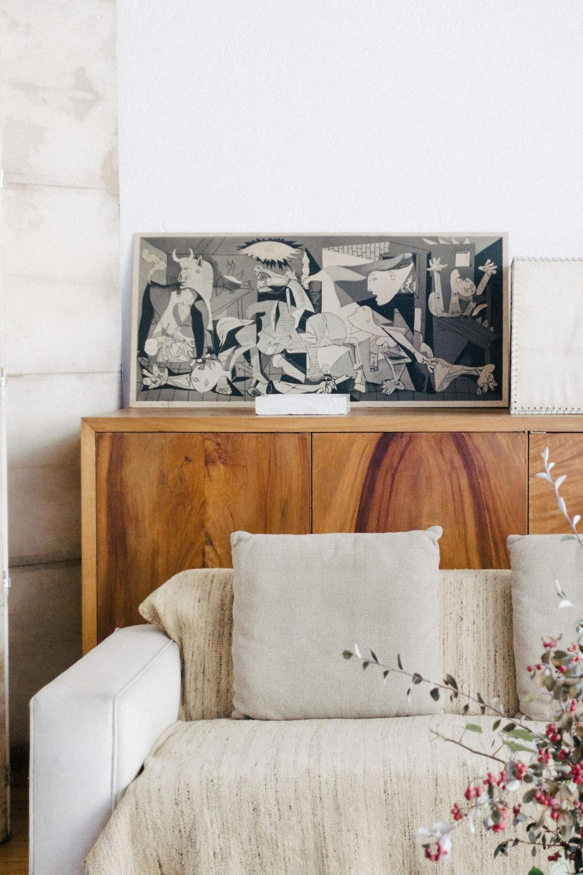 A cozy living room with a beige couch, cushions, a wooden cabinet, and a framed artwork on top at Northside Vistas apartments.