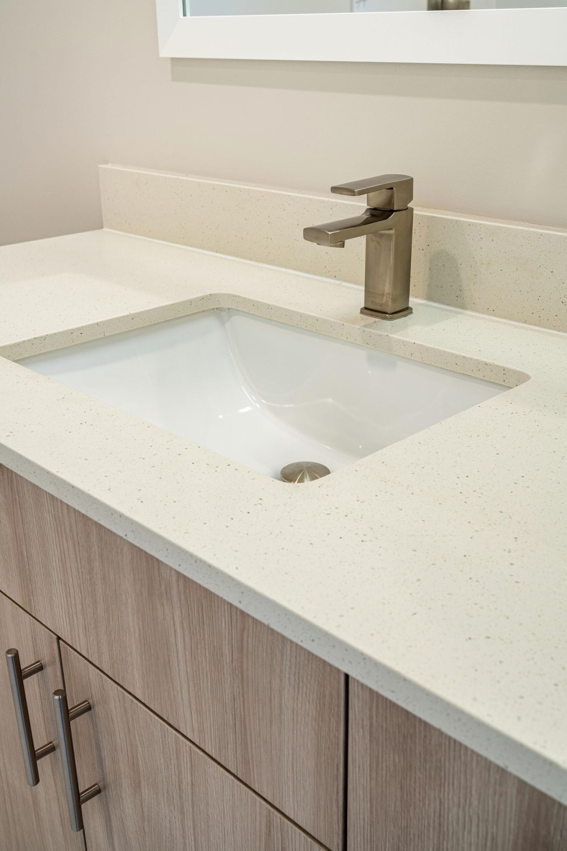 Northside Vistas apartments modern bathroom sink with a sleek faucet atop a beige countertop and light wood cabinetry.