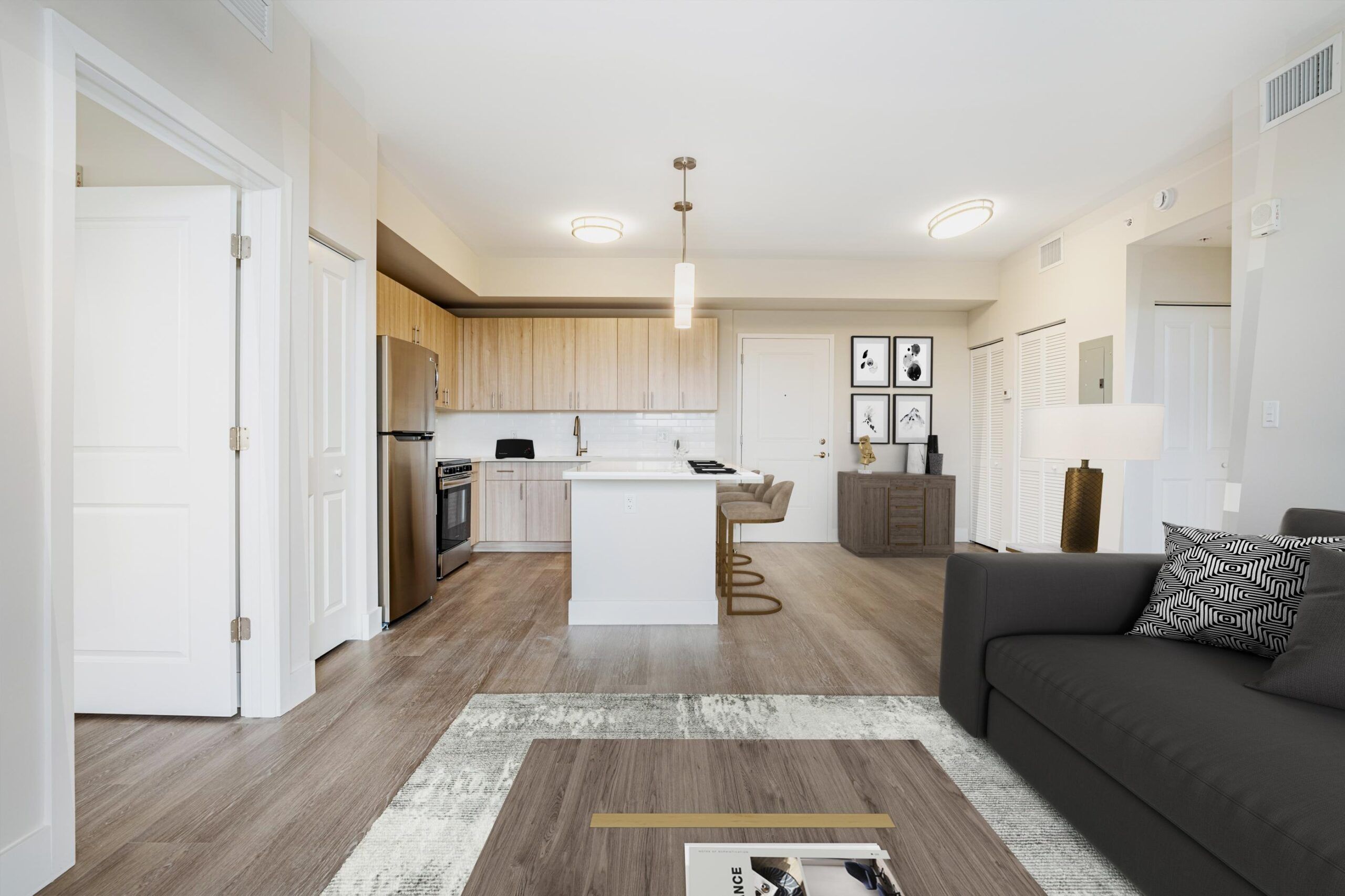 Northside Vistas apartments modern apartment interior with kitchen, island, and living area featuring a gray sofa and a rug on wooden floor.